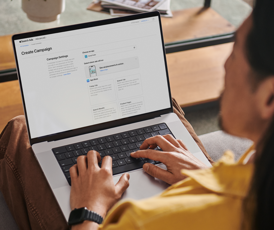 A person working on a MacBook creates a new campaign in Apple Ads.
